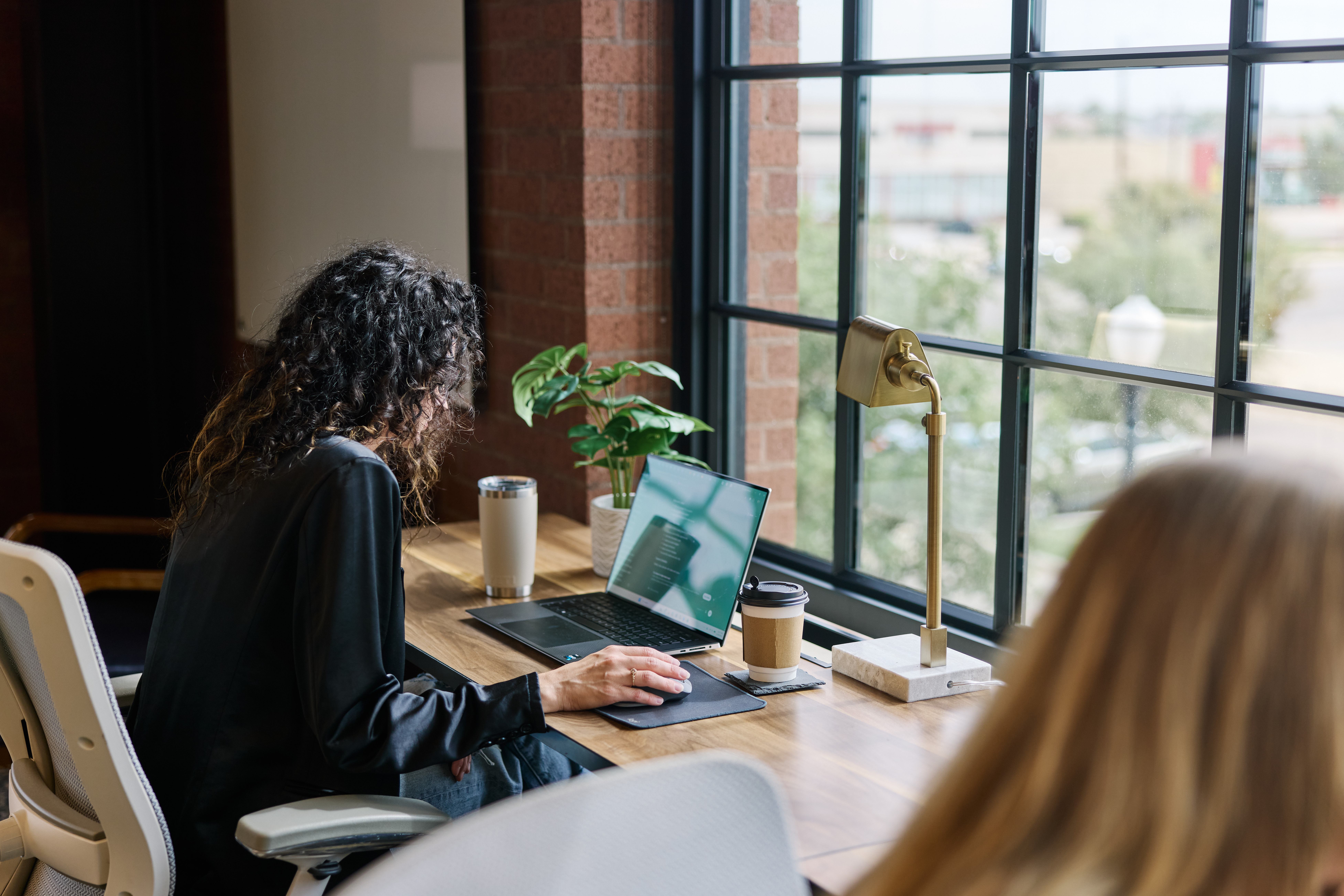 A member working focused at a sunlit window desk