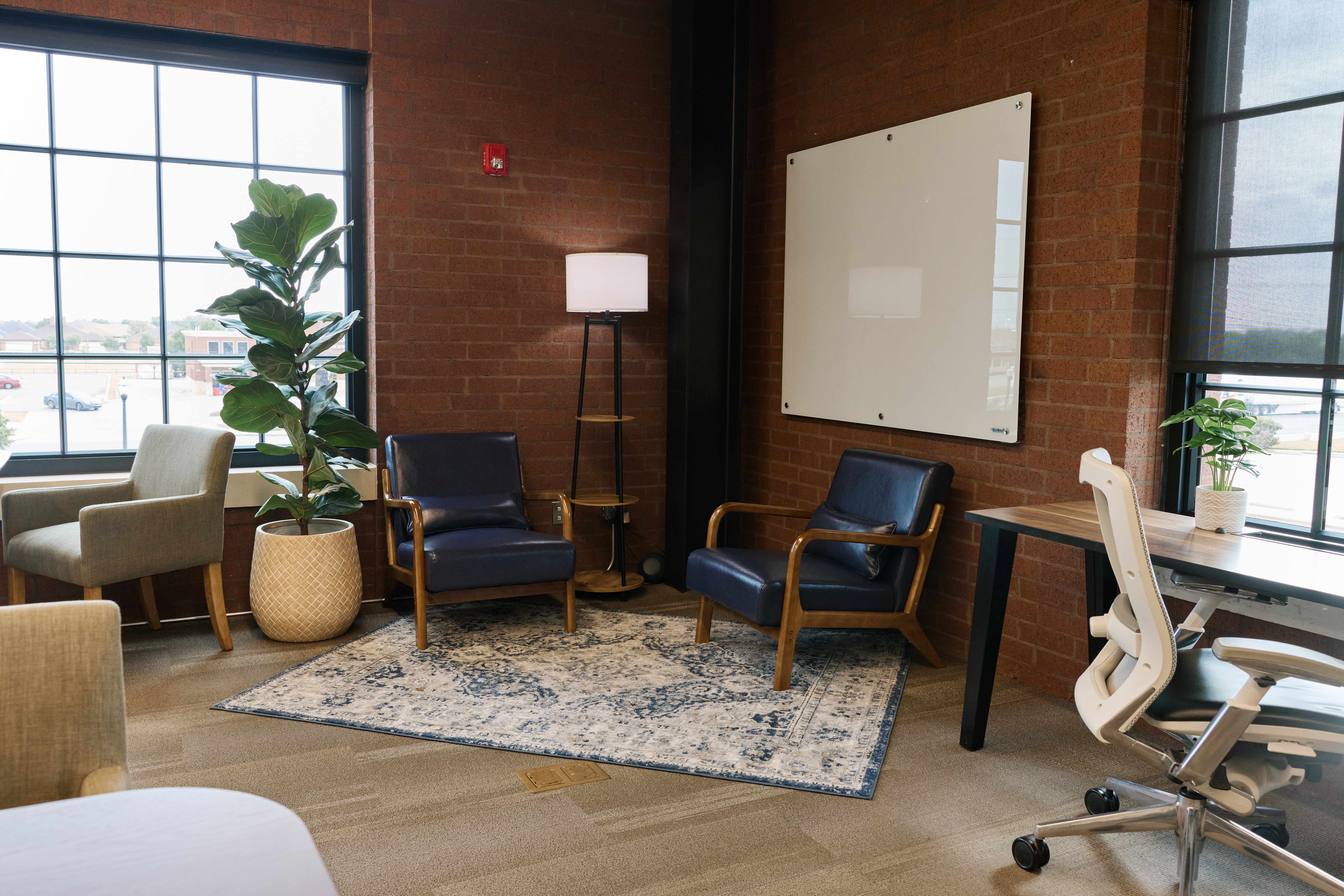 Comfortable lounge corner with leather chairs and a glass whiteboard